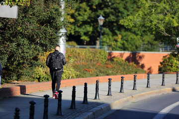 Młody mężczyzna z plecakiem i słuchawkami na uszach, idzie po moście we Wrocławiu.	
