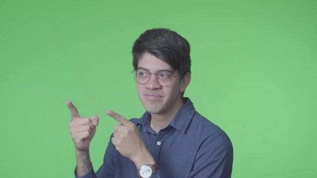 hombre latino se&ntilde;alando a un lado con las dos manos con fondo verde