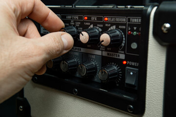 Close up of a man's hand adjusting an amplifier knobs