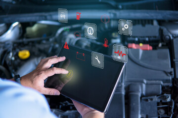 Auto mechanic with digital tablet at work making an engine repair diagnosis of a car in a mechanic...