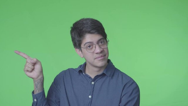 hombre latino diciendo si con la cabeza y Se&ntilde;alando a un lado con fondo verde