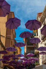 Pueblo celebrando la floración de la lavanda, paraguas morados colgados por las calles del pueblo, sombrillas fucsia flotando entre las calles