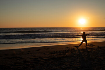 Fototapeta premium silhouette of woman exercising on the beach at sunset