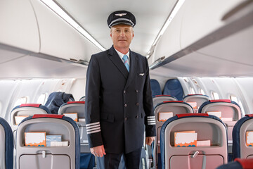 Male pilot standing in passenger airplane cabin