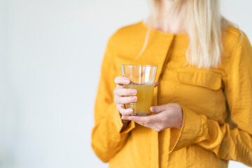 Blonde Frau hält ein Glas mit Saft in der hand