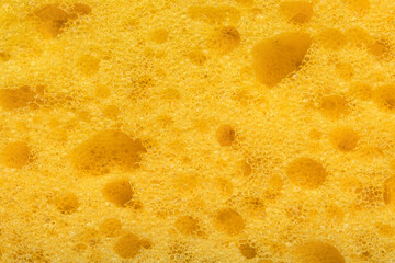 Foam sponge texture in macro. Textured background. Dishwashing or car cleaning concept. Abstract yellow wallpaper or backdrop for your design closeup 