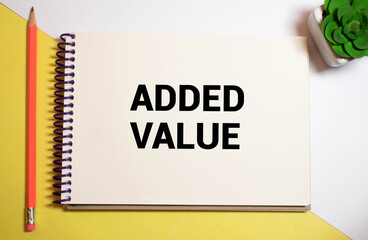 Added value text on notebook with laptop, pen, moblie phone and book on table