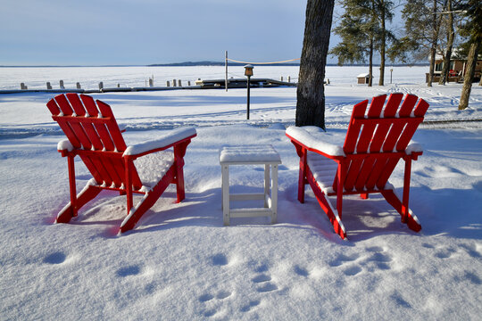 Empty red lawn chairs in winter snow