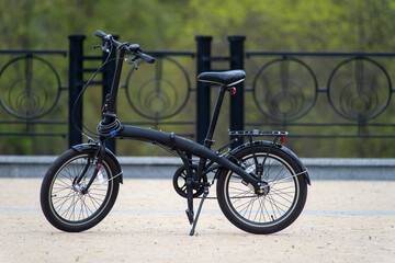 Folding black bike in the city park..