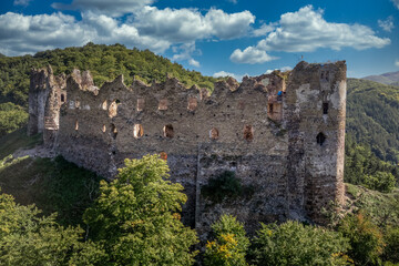 Aerial view of Sasovsky Hrad or Castle in central Slovakia above the Hron river with circular gate tower and adjacent  palace building on a steep mountain top