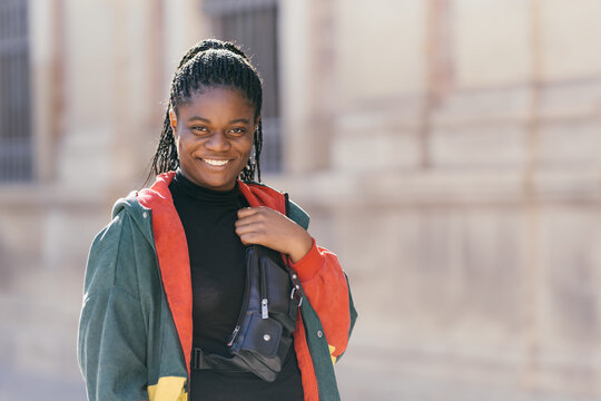 African Woman With A Fanny Pack Smiling At The Camera Outdoors