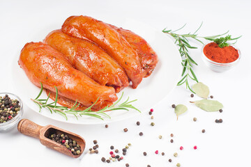 Fresh marinated chicken meat.Raw marinated chicken fillet in red sauce on a white plate on a light background with fresh rosemary leaves and spices.
