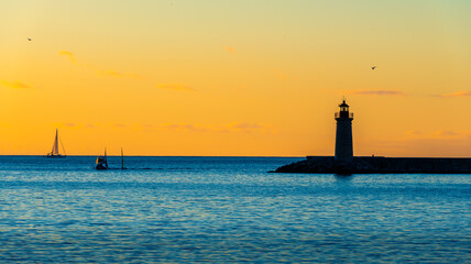 Fototapeta premium sunset over the sea with a clear sky and a lighthouse in the foreground 