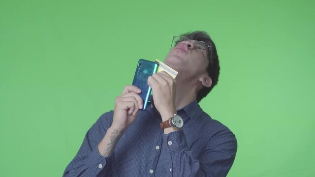 Hombre latino comprando en linea usando la tarjeta de cr&eacute;dito con fondo verde
