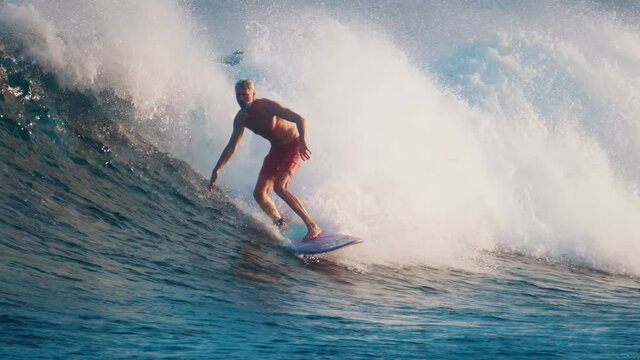 Elderly man surfs the wave in the ocean. Sultans surf spot in Maldives
