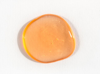 Orange cosmetics or antiseptic gel, cleaner or serum drop on white background. Colorful amber slime...