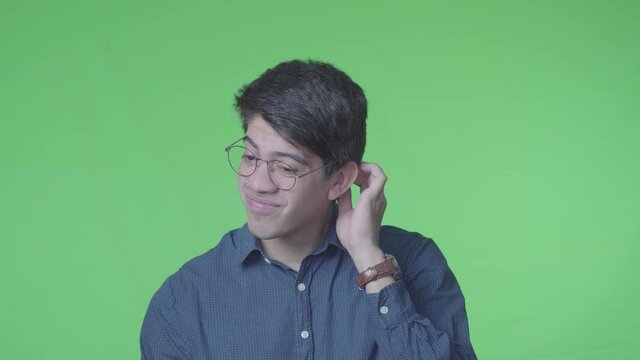 Hombre dudoso preguntando con su expreci&oacute;n corporal y fondo verde