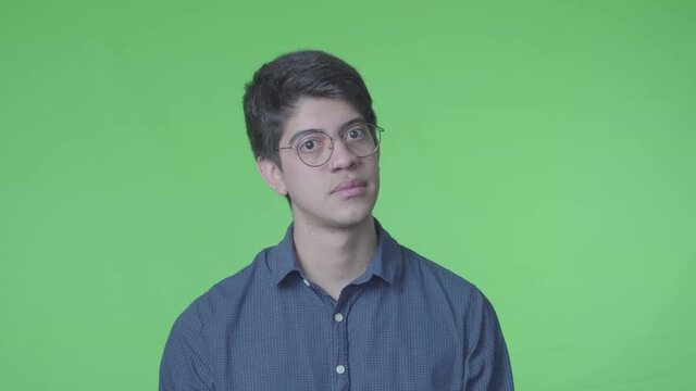 Hombre dudoso preguntando con su expreci&oacute;n corporal y fondo verde