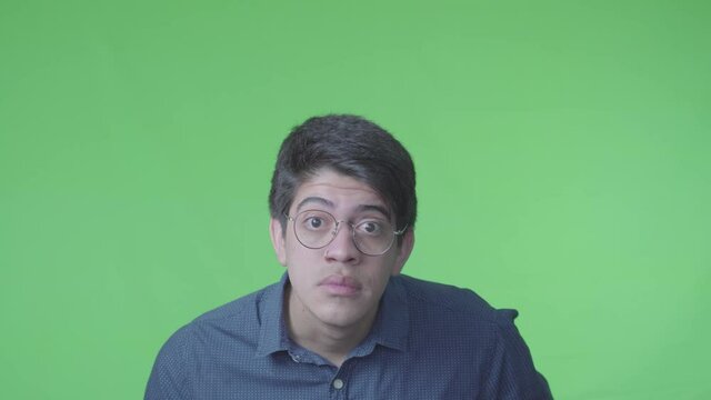 Hombre dudoso mirando bien hacia el frente con su expreci&oacute;n corporal y fondo verde