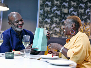 UK, Man giving gift to woman at restaurant table