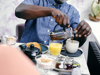 Fototapeta na wymiar UK, Man pouring coffee at breakfast table