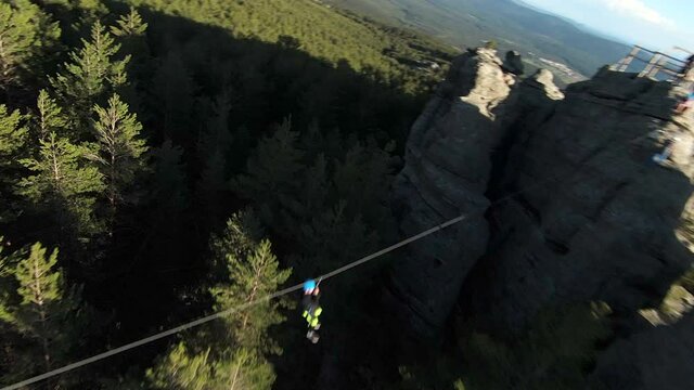 Aerial view of man cross over the trees by zipline in green nature. First person view, fpv.
