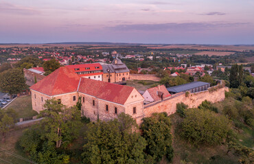 Fototapeta na wymiar Aerial sunset shot of Pecsvarad fortified church, abbey and castle with tower, gate on a hilltop in Baranya county Hungary with dramatic colorful sky