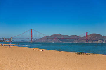 People on Golden Gate Beach, San Francisco, California, enjoying a sunny day and the view of Golden Gate Bridge.