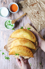 Girl's hands showing trio of empanada typical food from Venezuela with guasacaca sauce