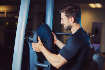 arrange weight discs at lifting machine at gym happily and satisfied looking forward to lift and...
