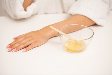 Beautician waxing female hands in spa center
