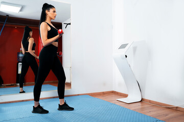 Side view, fit young woman in gym working out next to EMS machine 