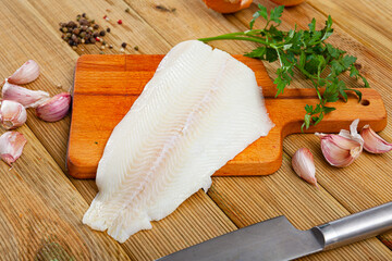 Raw halibut fillet, garlic, parsley on wooden table. Ingredients for cooking