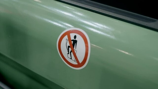 Picture (sign) on a manual hydraulic stacker with electric lift function showing unauthorized actions during operation. Shot in motion. Closeup