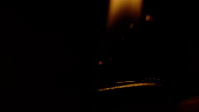 SLOW MOTION, MACRO, DOF: Orange flame rises from a lighter lit up at night. Macro view of a steel lighter ignited in the dark. Detailed close up shot of sparks flying as person ignites a lighter.