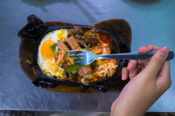 Beef jerky and fried eggs with sausages and salads are served on a black stone plate