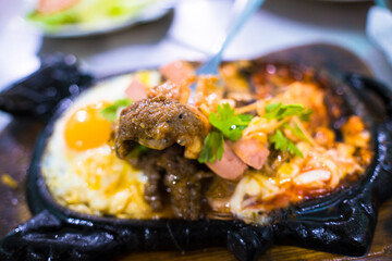 Beef jerky and fried eggs with sausages and salads are served on a black stone plate