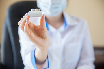 the doctor holds a mock-up of teeth in his hands