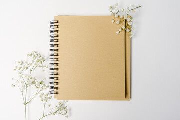 sketchbook brown sheet of paper notepad with spirals for planning top view and next to the white flower