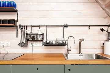 Kitchen brass utensils, chef accessories. Hanging kitchen with white tiles wall and wood...