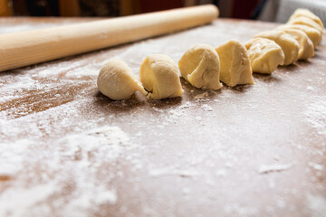 Stages of preparation from dough cut into small pieces lie on a dark table Top view.
Raw dough, cut...