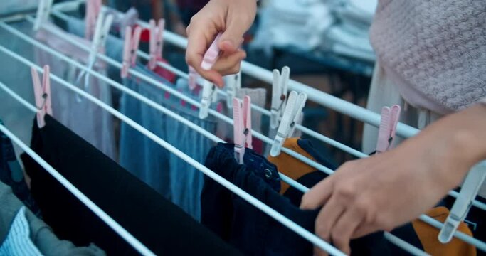Young attractive woman hanging up wet clean laundry with little toddler girl in terrace outdoors. Daughter helps to mother with chores at home