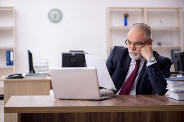 Naklejka premium Old male employee working in the office