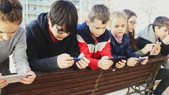 Kids using phones outdoors, concept of children addiction to social network