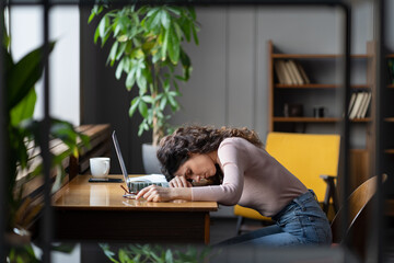 Tired businesswoman sleeping on table in office. Young exhausted girl lying on laptop keyboard,...