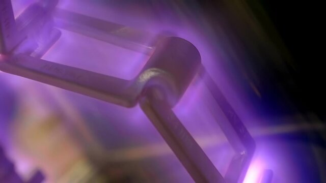 A metal structure in a vacuum and a beautiful mesmerizing plasma glow that has formed around the object. Shot in motion. Closeup