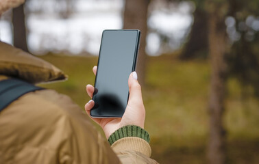 Young woman or teen girl holding mobile phone, light blank display, blank screen for social media app advertising at home.