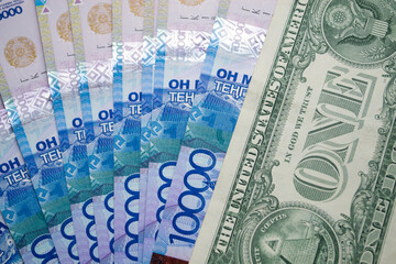 One dollar bill on the background of 10 000 tenge.