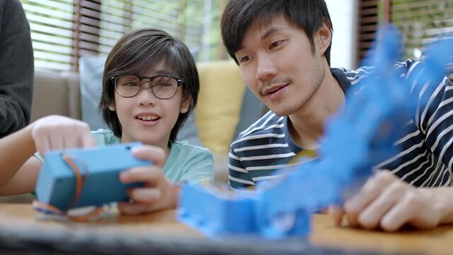 Remote learn online at home concept.asian boy child student remotely learn with father and mother in coding control robot arm on laptop and electronic board cable in STEM,robotics engineer at home.