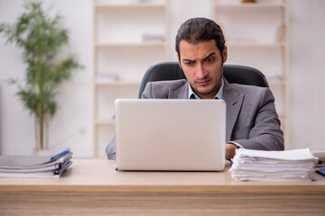 Young male employee unhappy with excessive work in the office